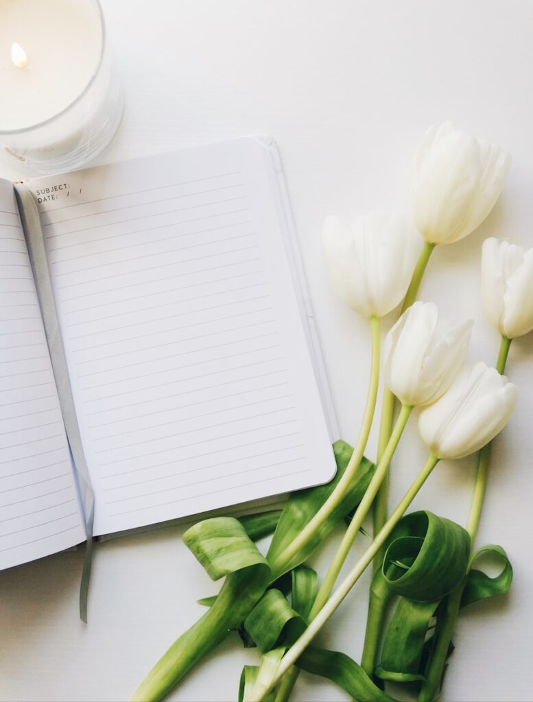 white flowers beside ruled paper sheet is a form of self love